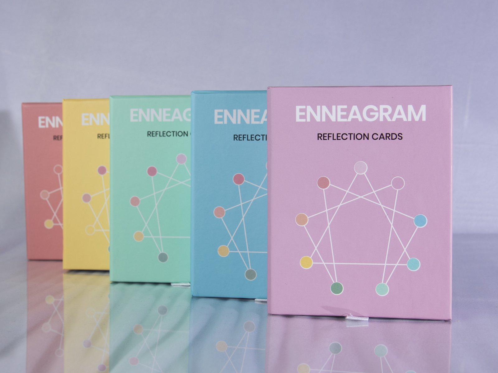 A row of colorful Enneagram Reflection Cards boxes